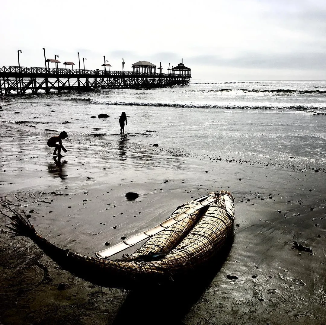 Enfants autour d'un caballito de totora sur la plage